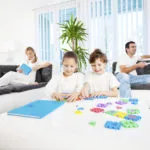 Children are smiling and playing with puzzle, in background their parents are enjoying. [url=http://www.istockphoto.com/search/lightbox/9786778][img]http://img143.imageshack.us/img143/364/familyyv.jpg[/img][/url]